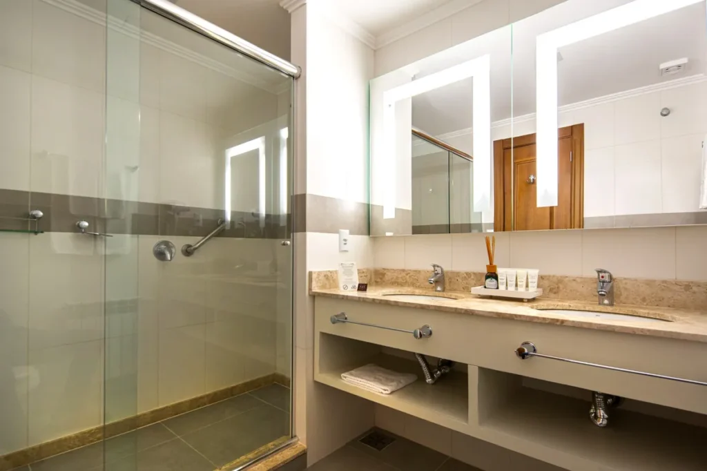 Banheiro da suíte Super Luxo do Hotel Alpestre com ducha box e bancada dupla.