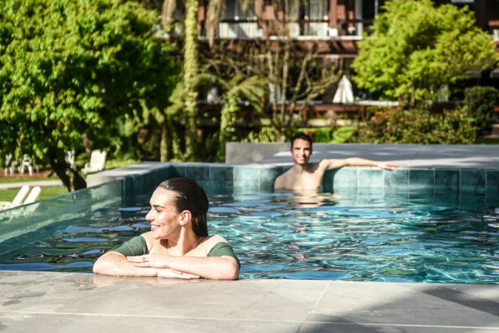 Casal relaxando na piscina externa do spa do Hotel Alpestre em Gramado cercado por natureza.