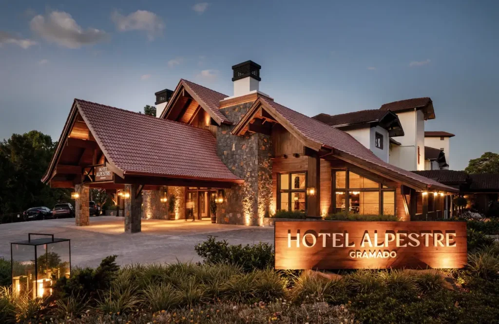 Fachada principal do Hotel Alpestre Gramado iluminada ao entardecer.