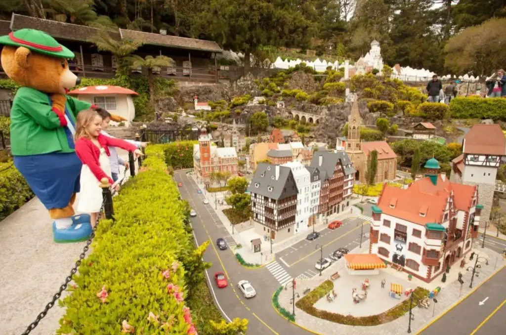 Famílias visitando o Mini Mundo em Gramado observando cidade em miniatura com prédios europeus e ruas detalhadas