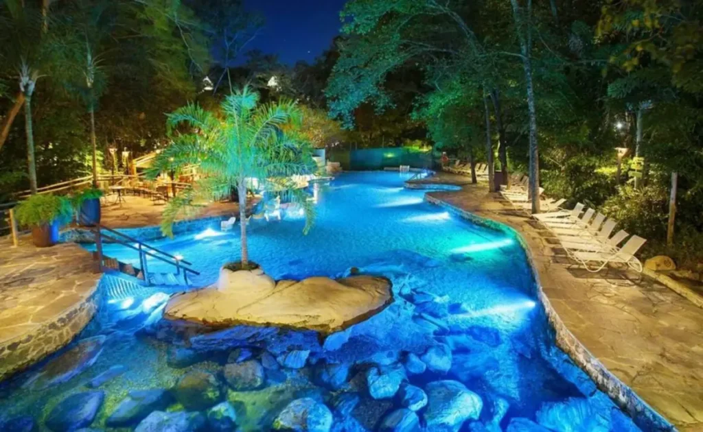 Piscina natural iluminada em meio à vegetação do Rio Quente Resorts.
