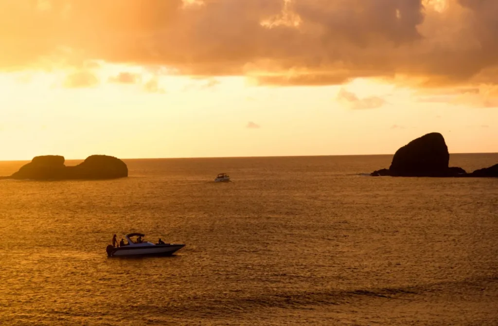 Barco navegando ao pôr do sol em Fernando de Noronha.