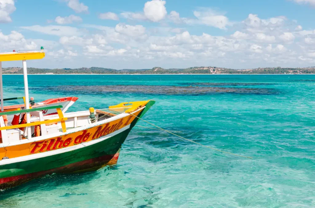 Barco colorido em águas cristalinas e azul-turquesa no litoral de Maragogi