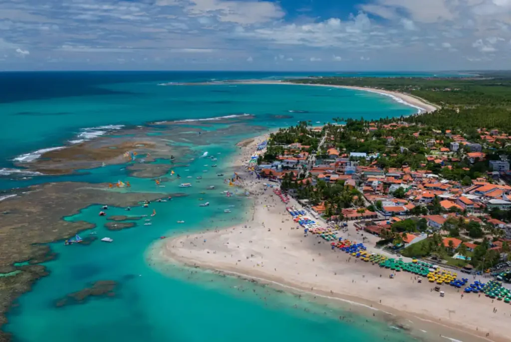 Piscina natural formada pelos arrecifes de Porto de Galinhas, em Pernambuco, com águas transparentes e visitantes durante a maré baixa.