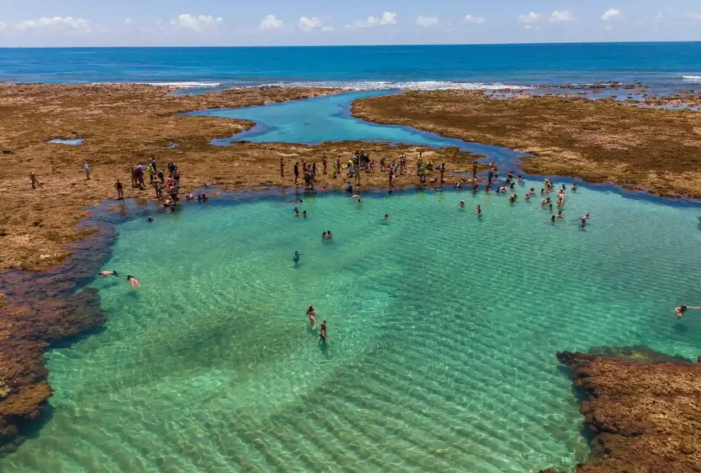 Praia de Porto de Galinhas com mar calmo protegido pelos arrecifes e águas azul-turquesa em Pernambuco.