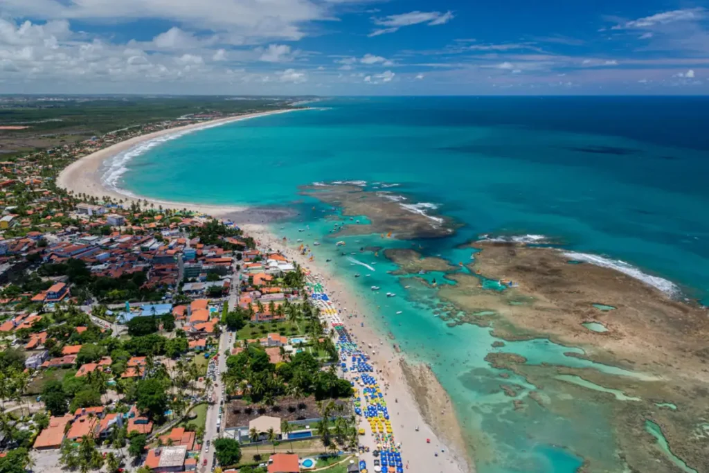 Vista panorâmica do centro de Porto de Galinhas, com piscinas naturais, faixa de areia e mar cristalino em Pernambuco.