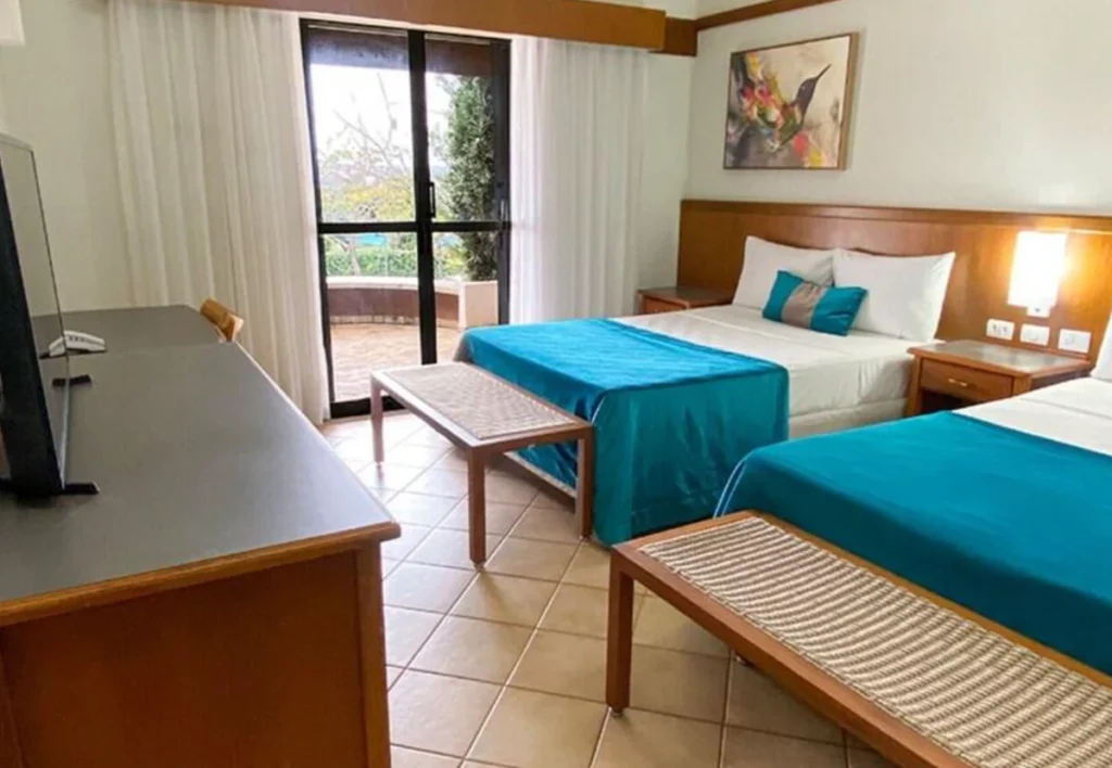 Quarto do Blue Tree Thermas de Lins com duas camas, televisão e acesso à varanda.
