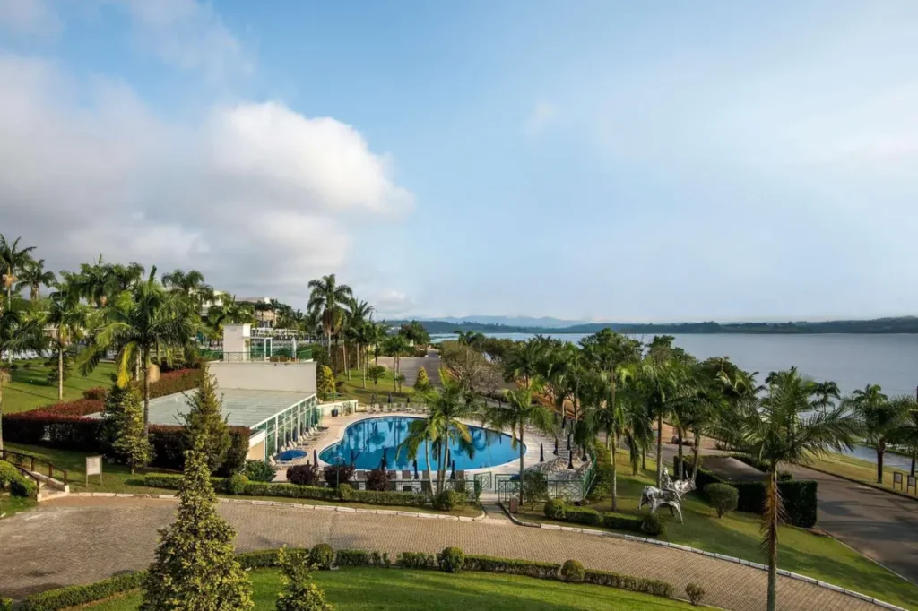 Piscina do Club Med Lake Paradise em meio aos jardins, com vista panorâmica para o lago.