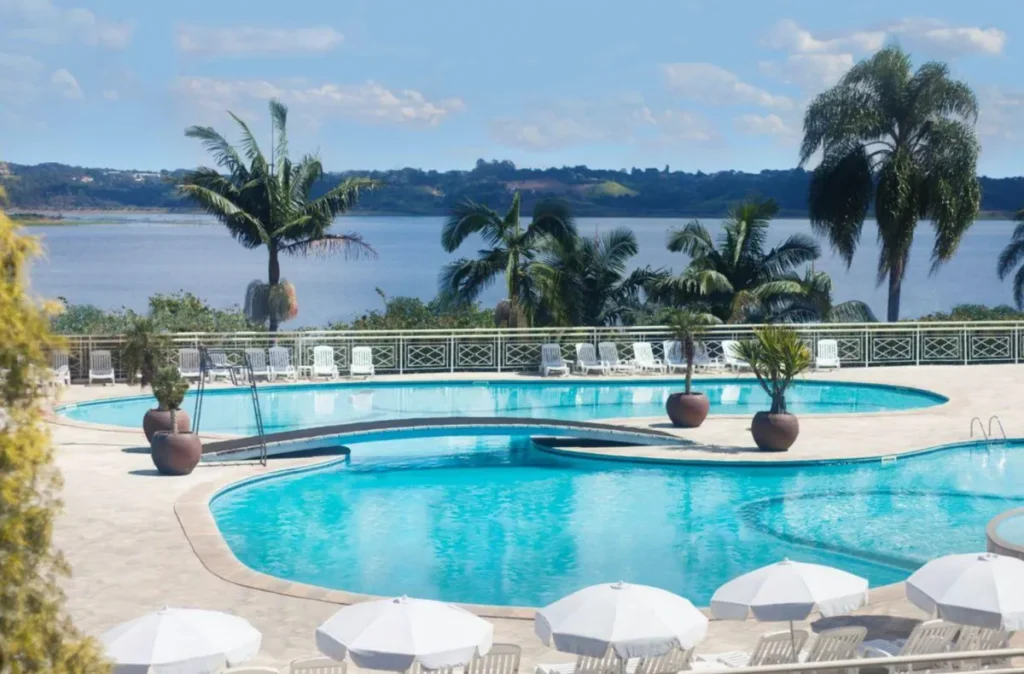 Área de piscinas do Club Med Lake Paradise cercada por palmeiras e com vista para o lago.