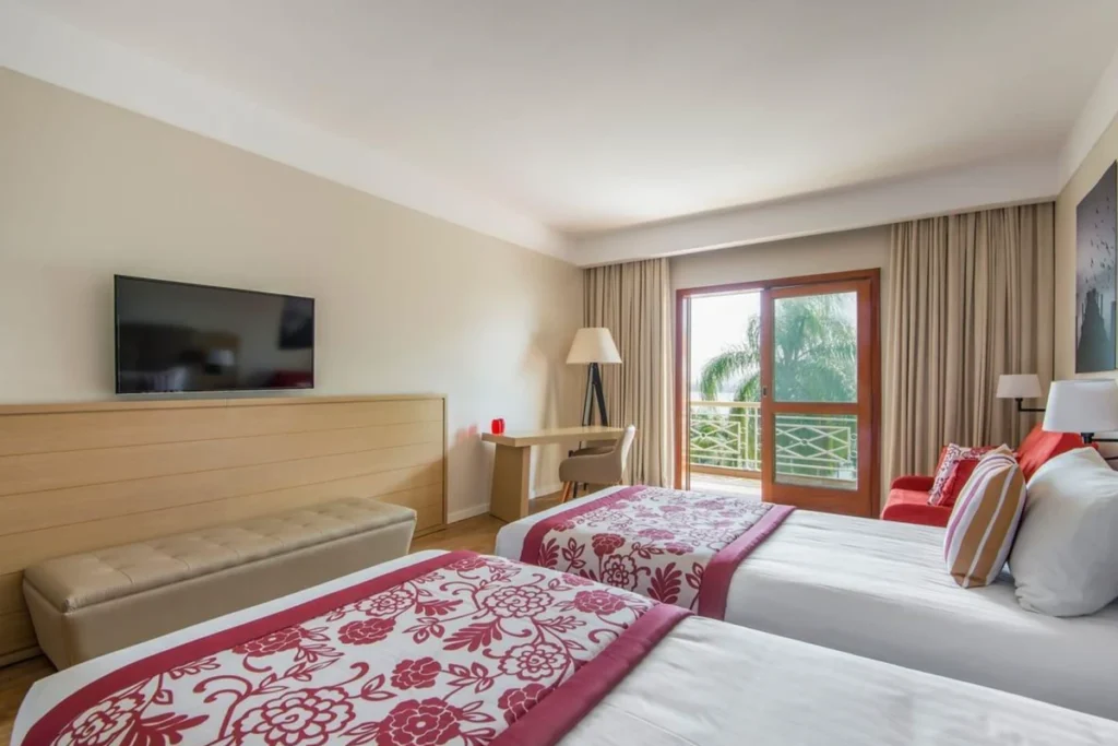 Quarto do Club Med Lake Paradise com duas camas, televisão, área de trabalho e varanda.