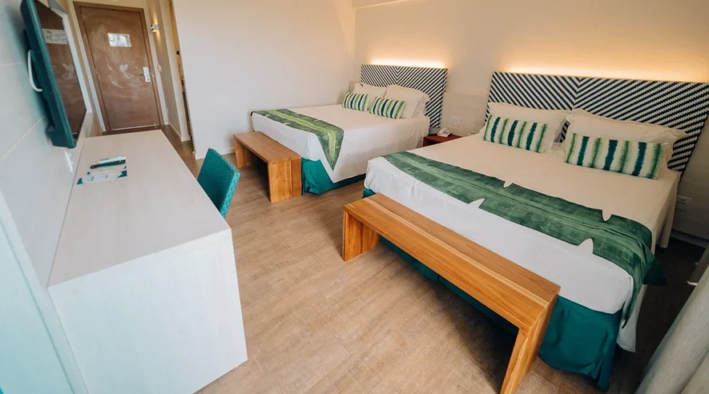 Acomodação familiar do Hot Beach Resort com duas camas, televisão e decoração contemporânea.