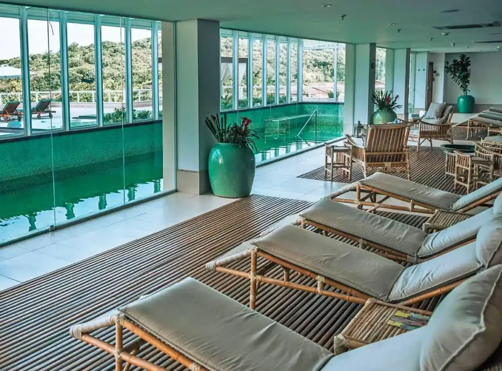 Área de relaxamento com piscina interna e espreguiçadeiras no Hotel Jequitimar Guarujá Resort & Spa.