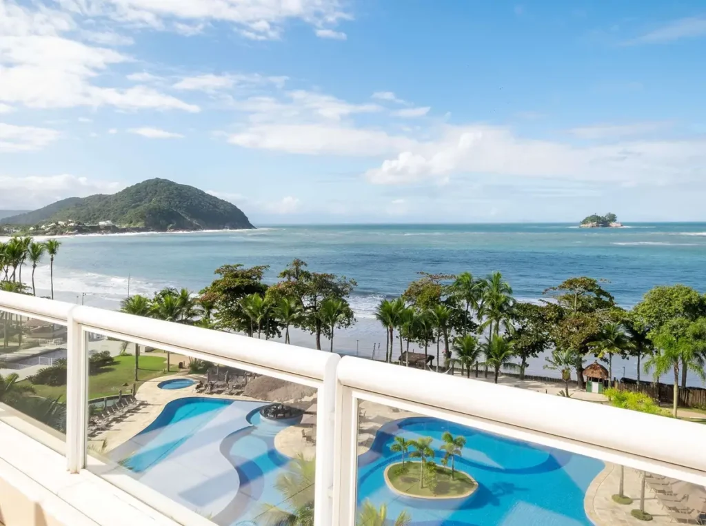 Área externa com ampla piscina e acesso à praia no Hotel Jequitimar Guarujá.
