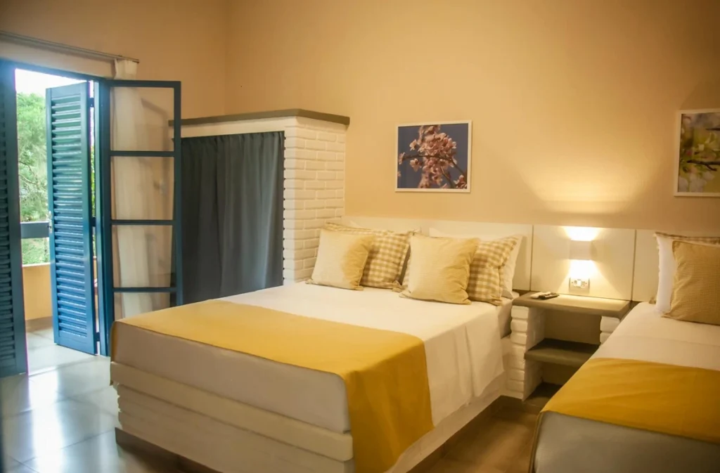Acomodação do Matiz Igaratá Resort com cama de casal, cama de solteiro e acesso à varanda.