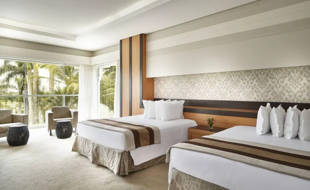 Quarto do Mavsa Resort com duas camas, varanda e vista para a área verde.