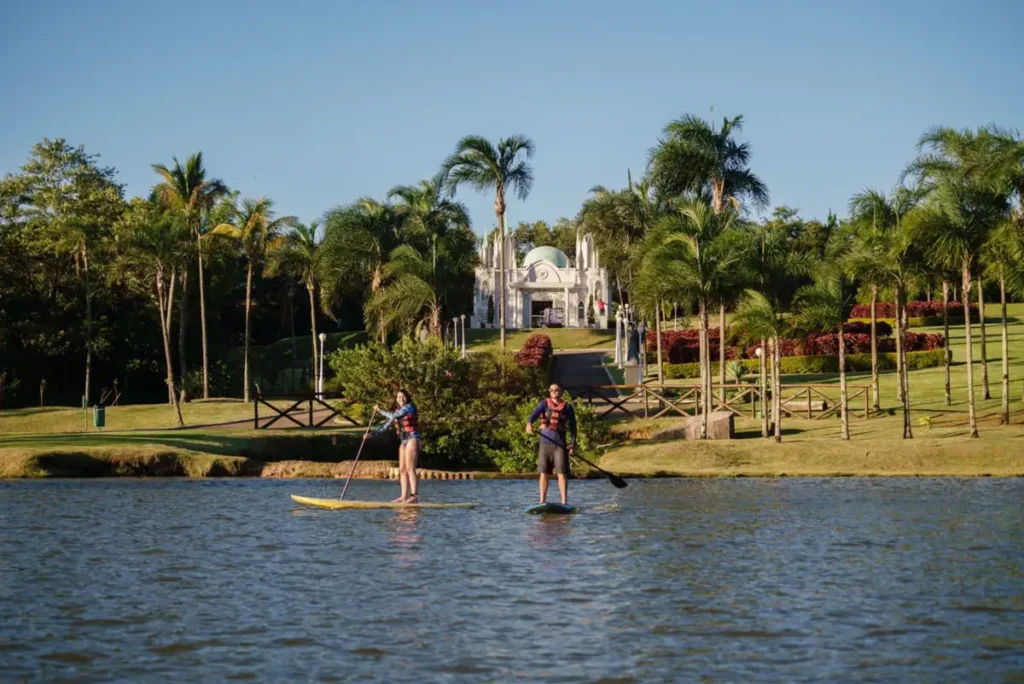 Atividade de stand up paddle no lago do Mavsa Resort, em meio à área verde.