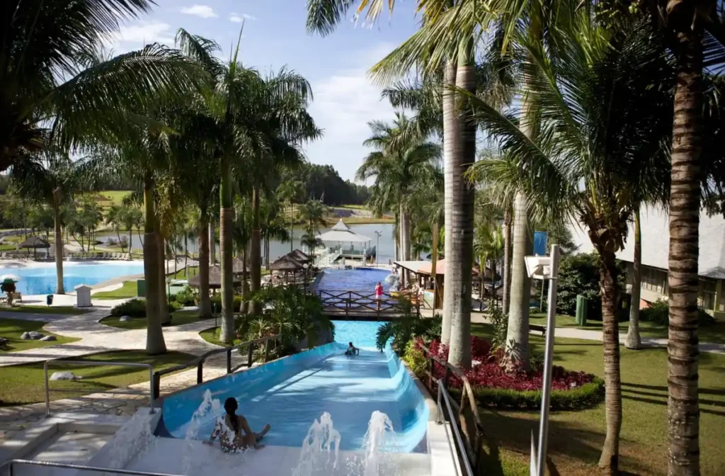 Área de lazer do Mavsa Resort com toboágua, piscinas, palmeiras e vista para o lago.