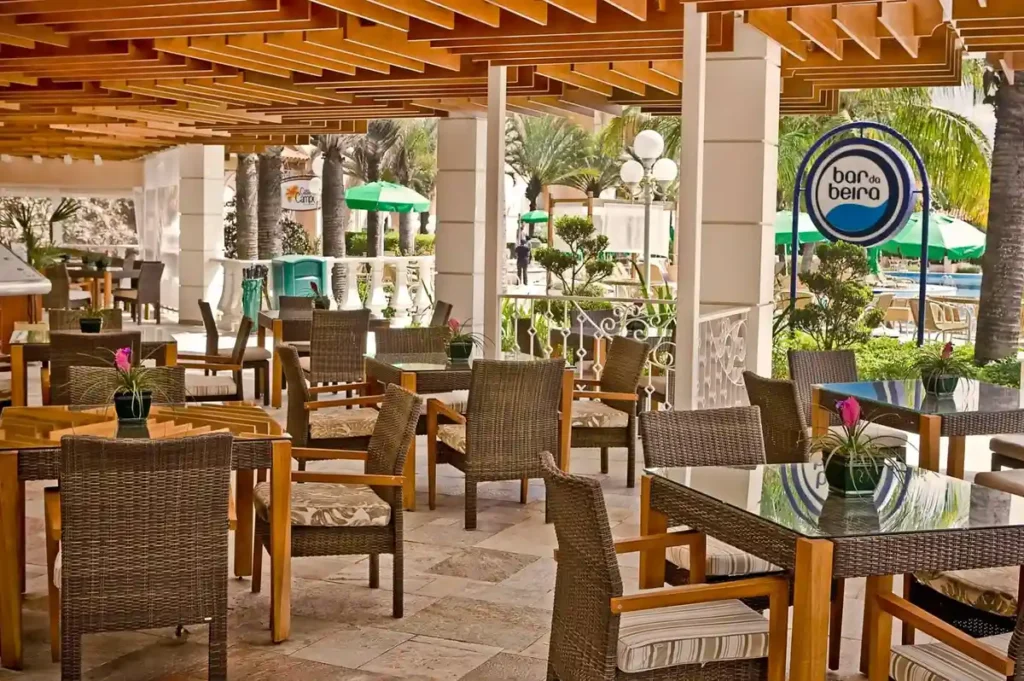 Mesas e área coberta do Bar da Beira, próximo à piscina do Royal Palm Plaza Resort.