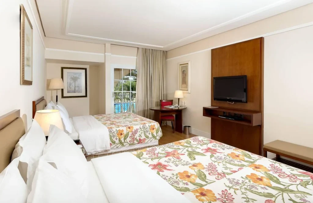 Quarto confortável com duas camas, TV e varanda no Royal Palm Plaza Resort.