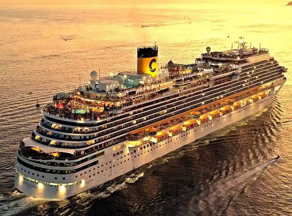Costa Diadema navegando ao entardecer, com seus decks iluminados e vista panorâmica do navio de cruzeiro.