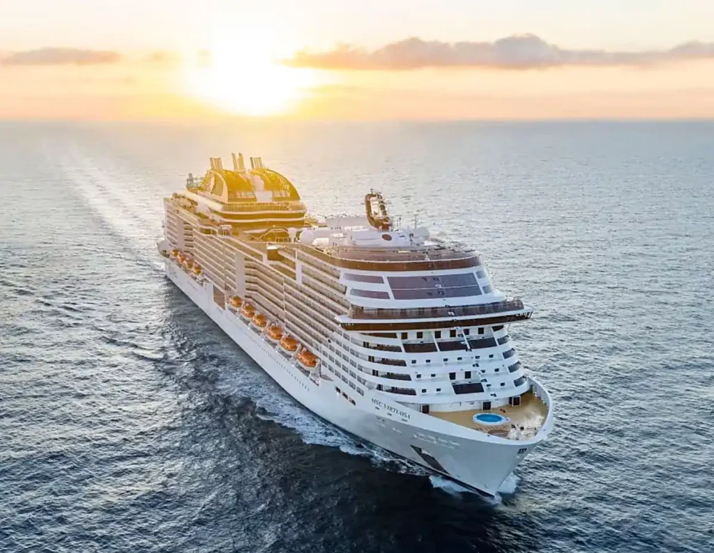 Cruzeiro Réveillon 2026 - MSC Virtuosa, navio de cruzeiro da MSC Cruzeiros, navegando em alto-mar durante um pôr do sol.
