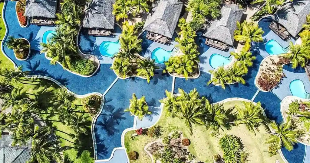 Vista aérea do Nannai Resort Muro Alto, resort de luxo em Porto de Galinhas, com bangalôs cercados por piscinas e coqueiros.