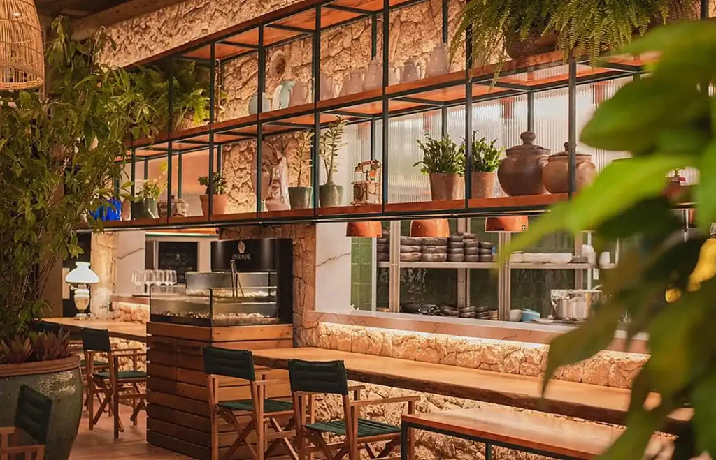 Ambiente gastronômico com decoração rústica sofisticada, elementos naturais e cozinha aberta.